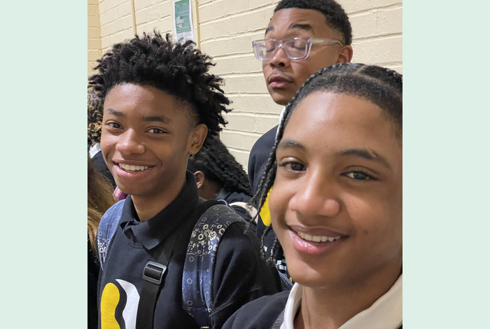 a boy with freeform locs standing by a boy in braids and a boy in glasses