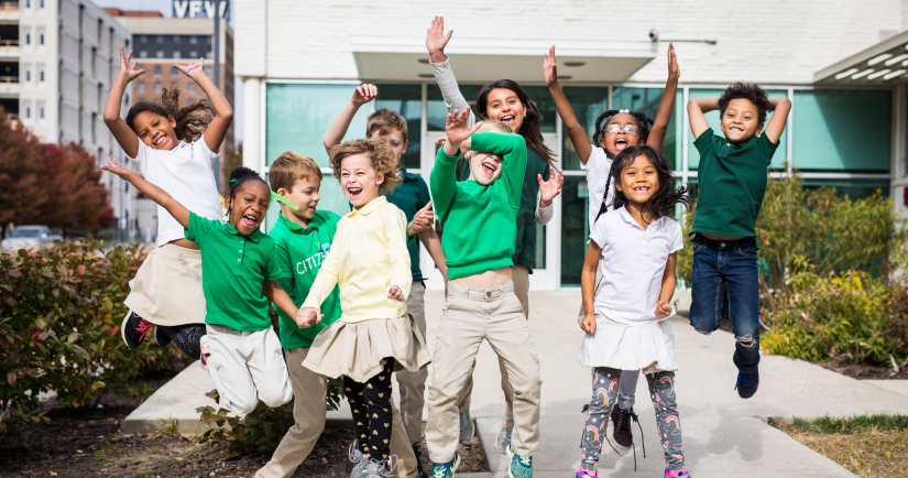 A group of charter school kids in uniform jumping up and down.