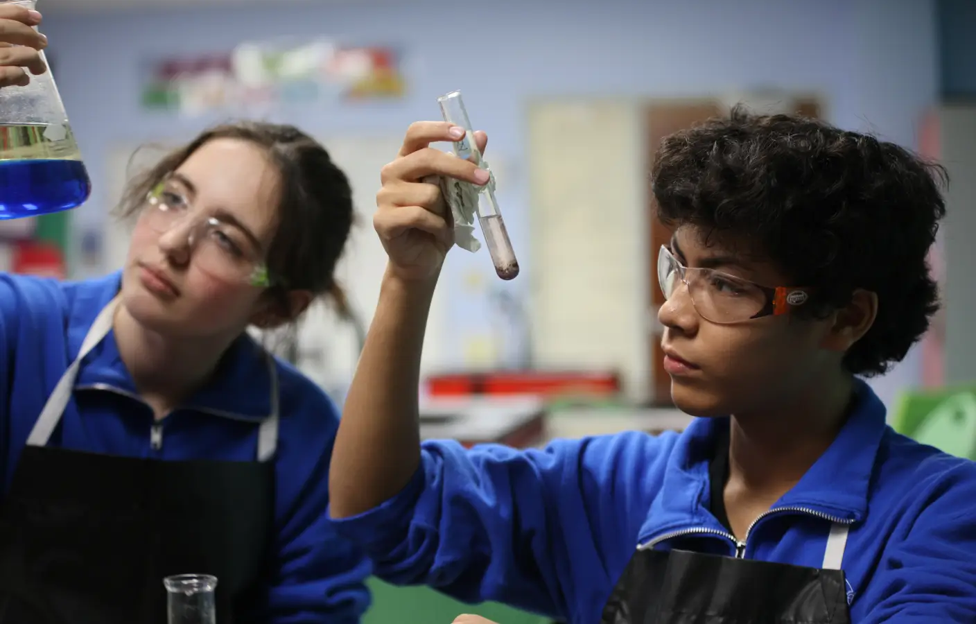 STEM students holding up and looking at test tubes.