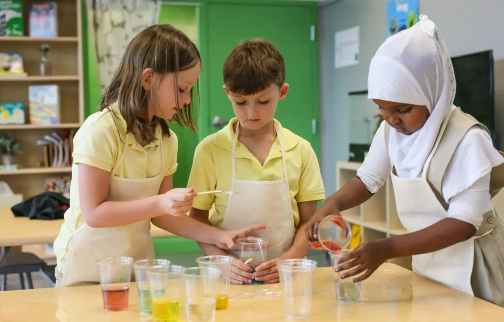 Kids standing in school room, mixing colorful liquids